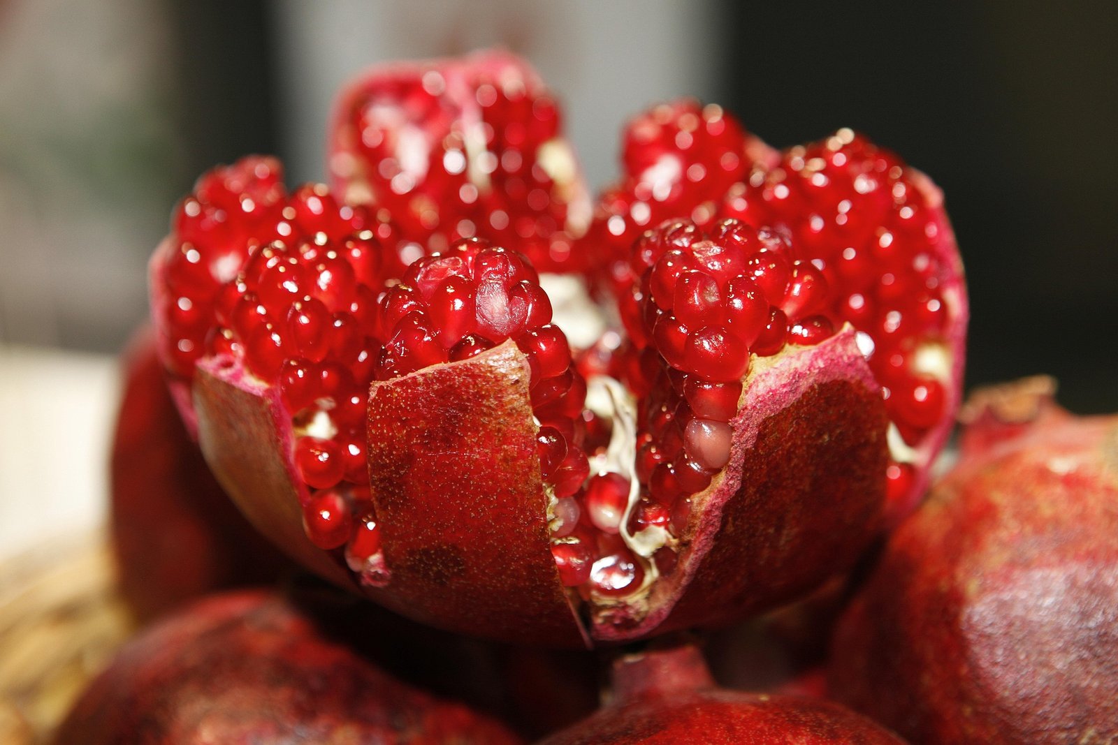 roma-beneficios-e-composicao romã aberta com arilos vermelhos - fruta rica em antioxidantes, vitamina C e fibras - ideal para saladas e sobremesas